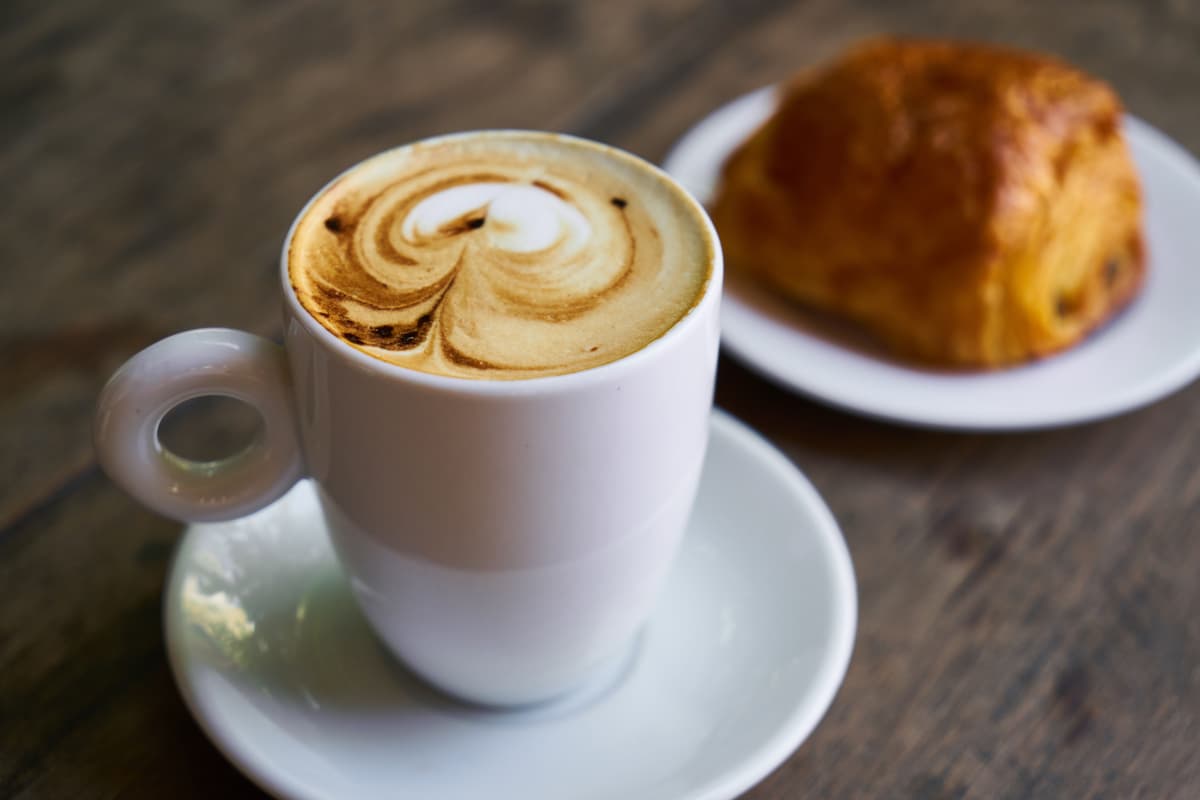 A plate of fresh pastries next to a latte